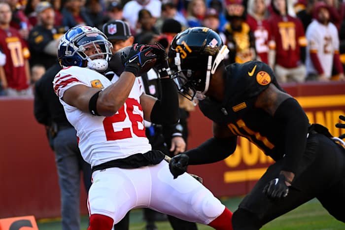 New York Giants running back Saquon Barkley (26) catches a touchdown past Washington Commanders safety Kamren Curl (31) during the first half at FedExField.